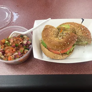 Avocado, sprout, tomato on an everything wheat bagel. Along side an Israeli salad.