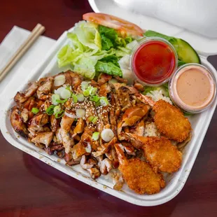 a tray of asian food with chopsticks and sauce