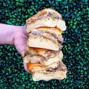 a hand holding a stack of sandwiches