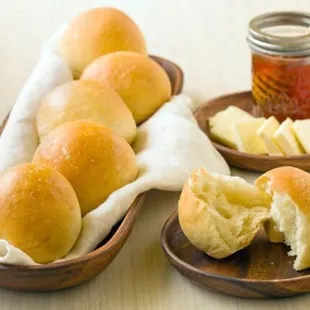 a plate of bread rolls with butter and a jar of honey