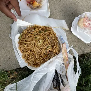 a person eating noodles in a plastic container