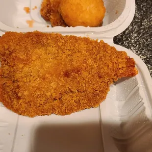 a piece of fried chicken in a styrofoam container