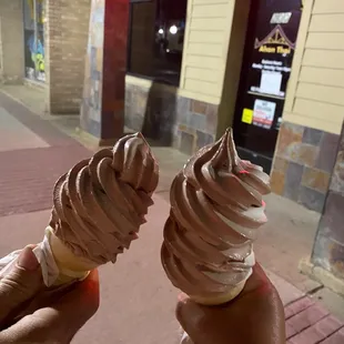 two hands holding two cones of ice cream