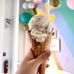 a hand holding a cone of ice cream