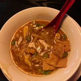 a bowl of soup with a red spoon