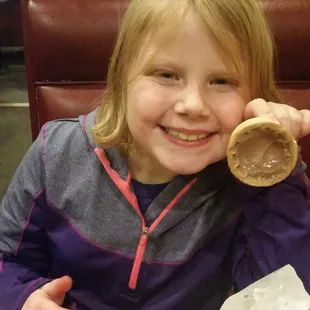 a little girl sitting at a table with a donut