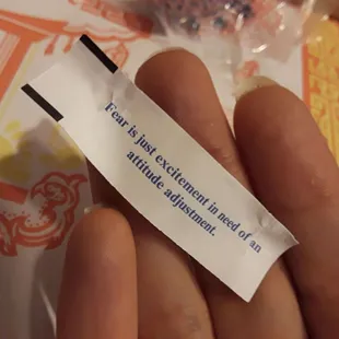 a hand holding a piece of paper with writing on it