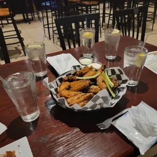 a basket of fried wings and a glass of water