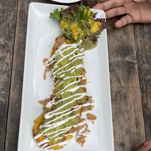 Patacon/flattened and fried giant green plantain slice with topping of shredded chicken, guacamole and sour cream!