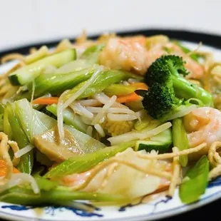 a plate of noodles with shrimp and vegetables