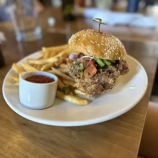 Pork Milanese sandwich with avocado and pico de gallo as well as fries.