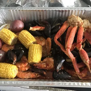 crab legs, potatoes, corn, and potatoes in a foil container