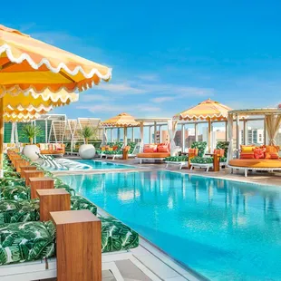 an outdoor pool with lounge chairs and umbrellas