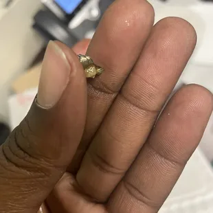 a person&apos;s hand holding a tiny ring
