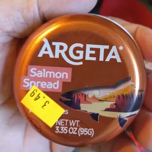 a person holding a jar of salmon spread