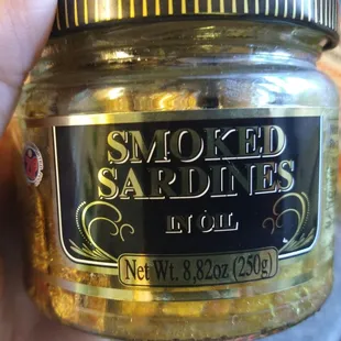 a hand holding a jar of smoked saldines