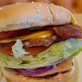 a hamburger with bacon, lettuce, tomato, and cheese