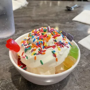 Ice cream sundae with strawberry sauce and banana, gummy bears, and sprinkles