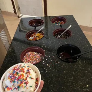 a person holding a bowl of ice cream with sprinkles