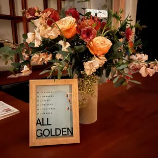 a vase of flowers and a sign on a table