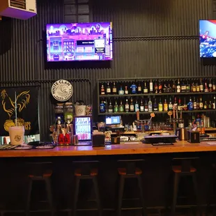 a bar with bar stools and televisions