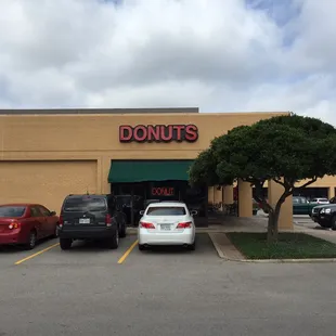 a donut shop with cars parked in front