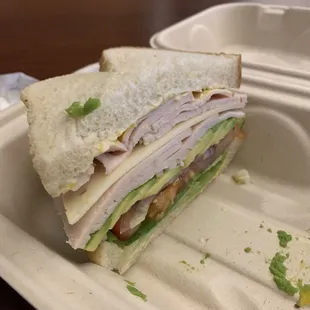 a cut in half sandwich in a styrofoam container