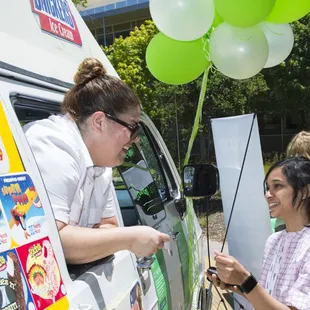 a woman handing a balloon to a girl
