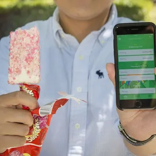 a man holding a candy bar and a cell phone