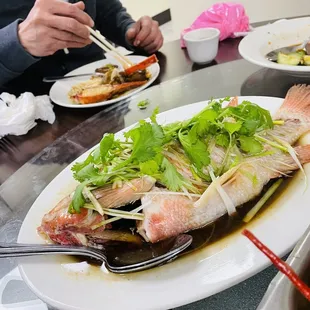 a man eating a fish with chopsticks