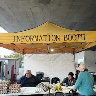 a man and a woman sitting at a table under a yellow tent