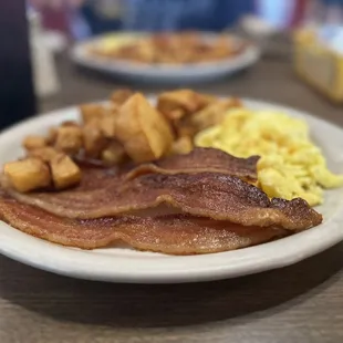 a plate of bacon, eggs, and hash browns