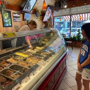 a woman standing in front of a gelato case