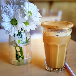 a glass of coffee and a vase of flowers