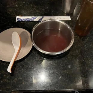 a bowl of liquid and a spoon on a counter