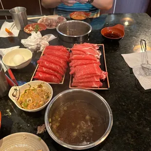 a man sitting at a table with bowls of food and chopsticks