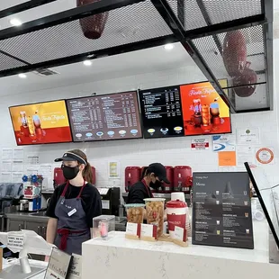 a restaurant counter with a woman wearing a face mask