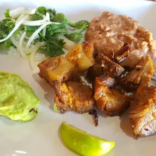 a plate of food with beans, potatoes, and guacamole