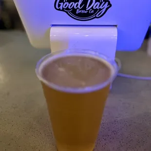 a cup of beer in front of a cooler