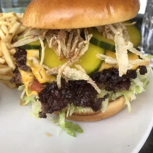 Cheese burger loaded up with house made pickles, crispy shallots, lettuce and tomato