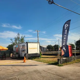 Street view of Good Day pizza&apos;s food truck. Look for the large flags. Located right near Harvest City Church.