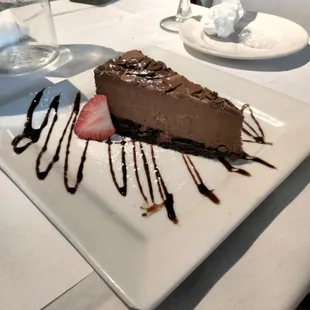 a piece of chocolate cake with strawberries and chocolate sauce