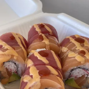 four sushi rolls in a styrofoam container