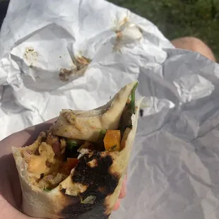 a person holding a burrito in their hand