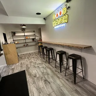 a row of stools in front of a neon sign
