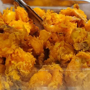 a bowl of fried food with tongs