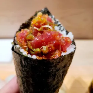 a hand holding a piece of sushi