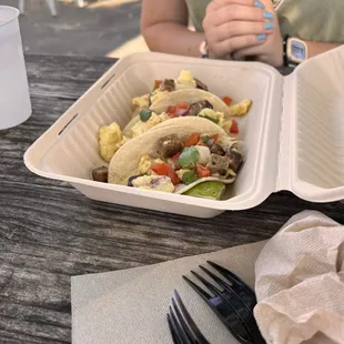 a woman holding a fork and a tray of food