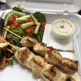 a salad and chicken skewers
