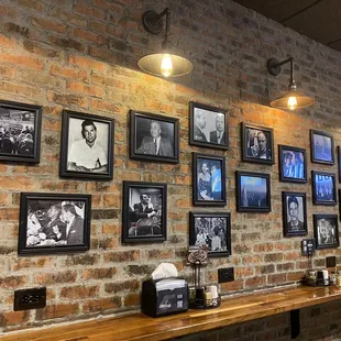 a brick wall full of framed photos